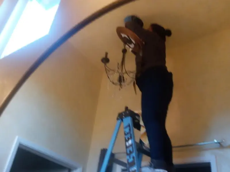 Electrician installing a chandelier in a Lake Cassidy residence